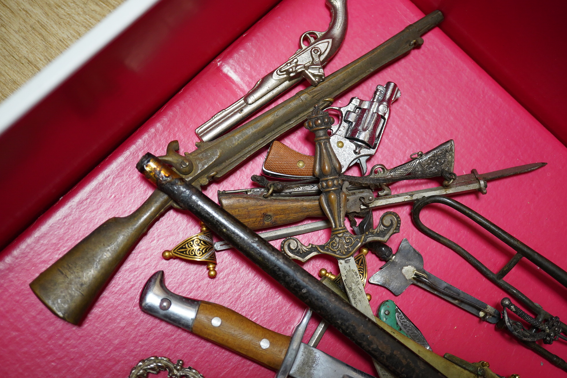 A large collection of miniature weapons, comprising approximately thirty-four edged weapons, and thirteen assorted firearms, approximately half contained within a mahogany case. Condition - fair to good